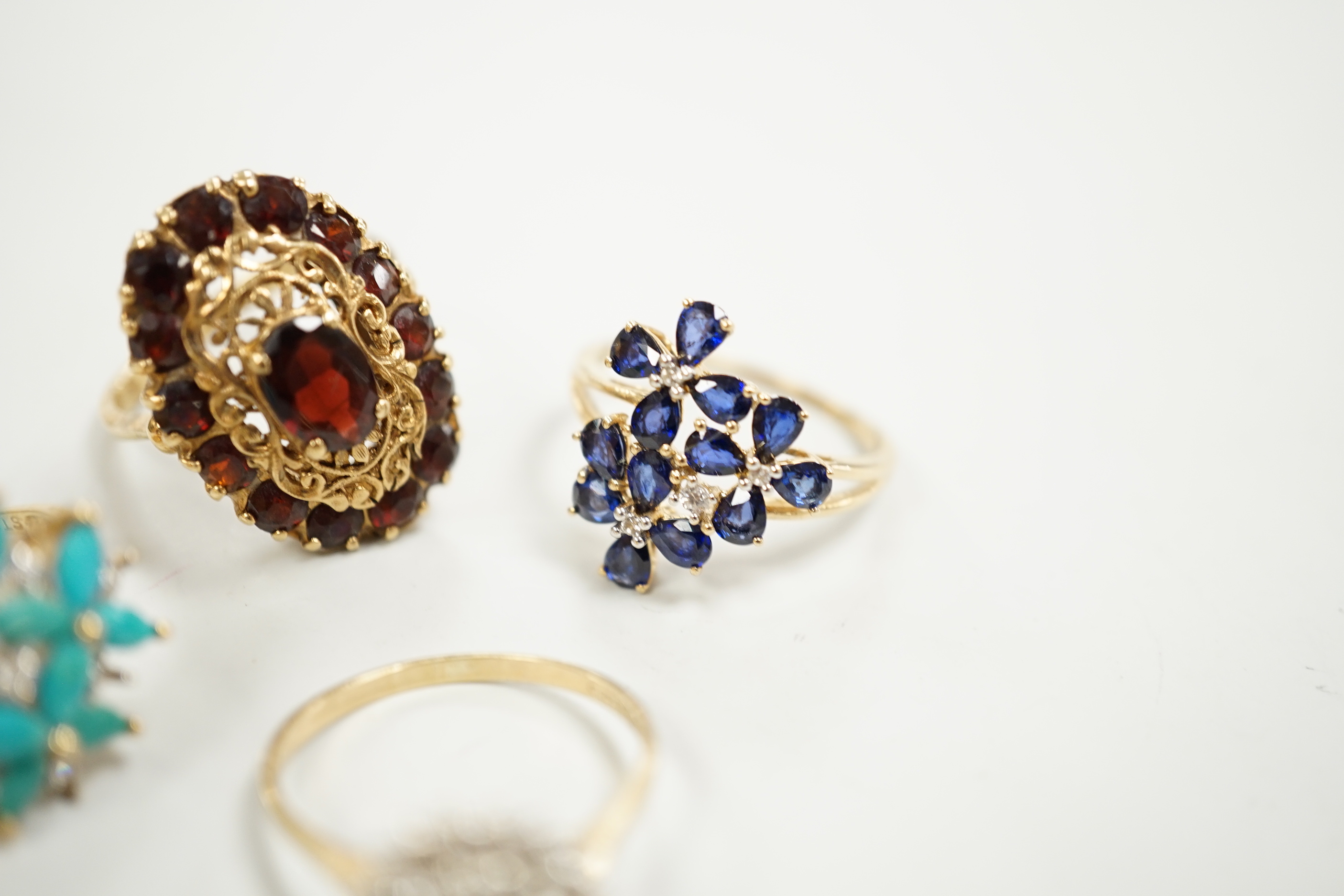 Four assorted modern 9ct gold and gem set dress rings including diamond cluster and garnet cluster, gross weight 13.6 grams.